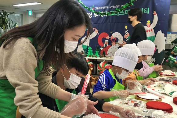  CJ올리브네트웍스 임직원이 결연 사회복지기관에서 아이들과 함께 크리스마스 케이크를 만들고 있는 모습 